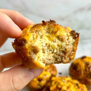 hand holding Bisquick sausage muffin with bite taken out of it.