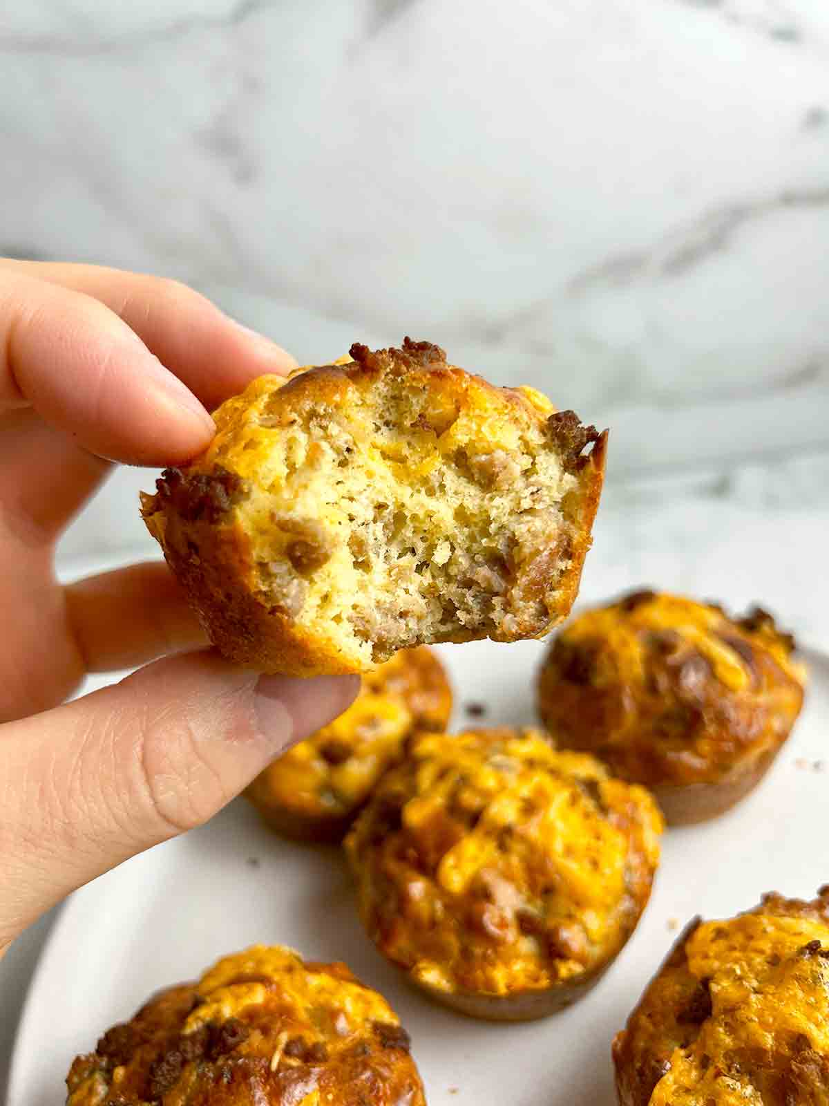 hand holding Bisquick sausage muffin with bite taken out of it.