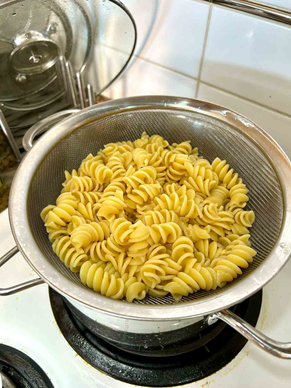 cooked rotini pasta draining over pot.