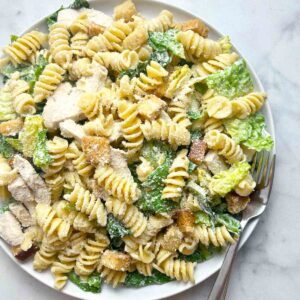 overhead shot of chicken caesar pasta salad on plate with fork.