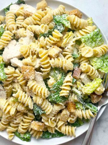 overhead shot of chicken caesar pasta salad on plate with fork.