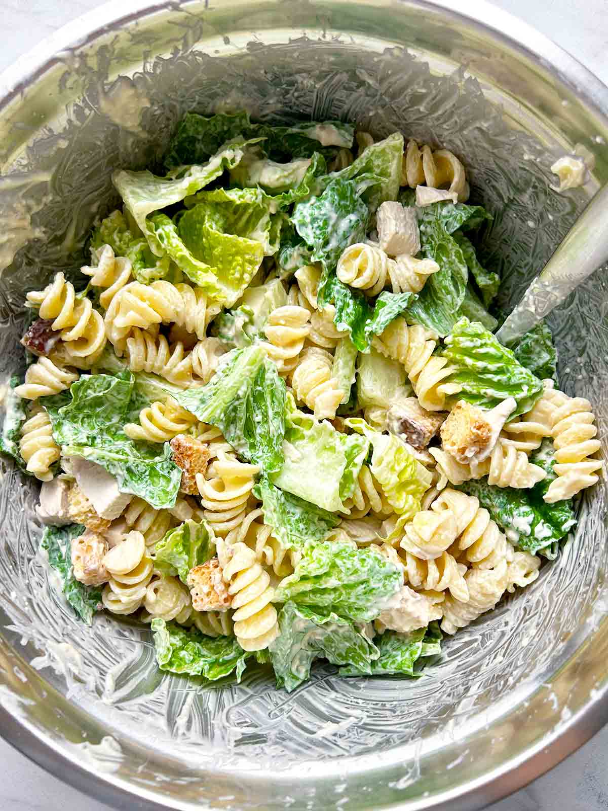 caesar salad ingredients mixed together in bowl.