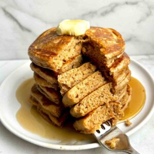 stack of cinnamon brown sugar pancakes with section cut down through middle.