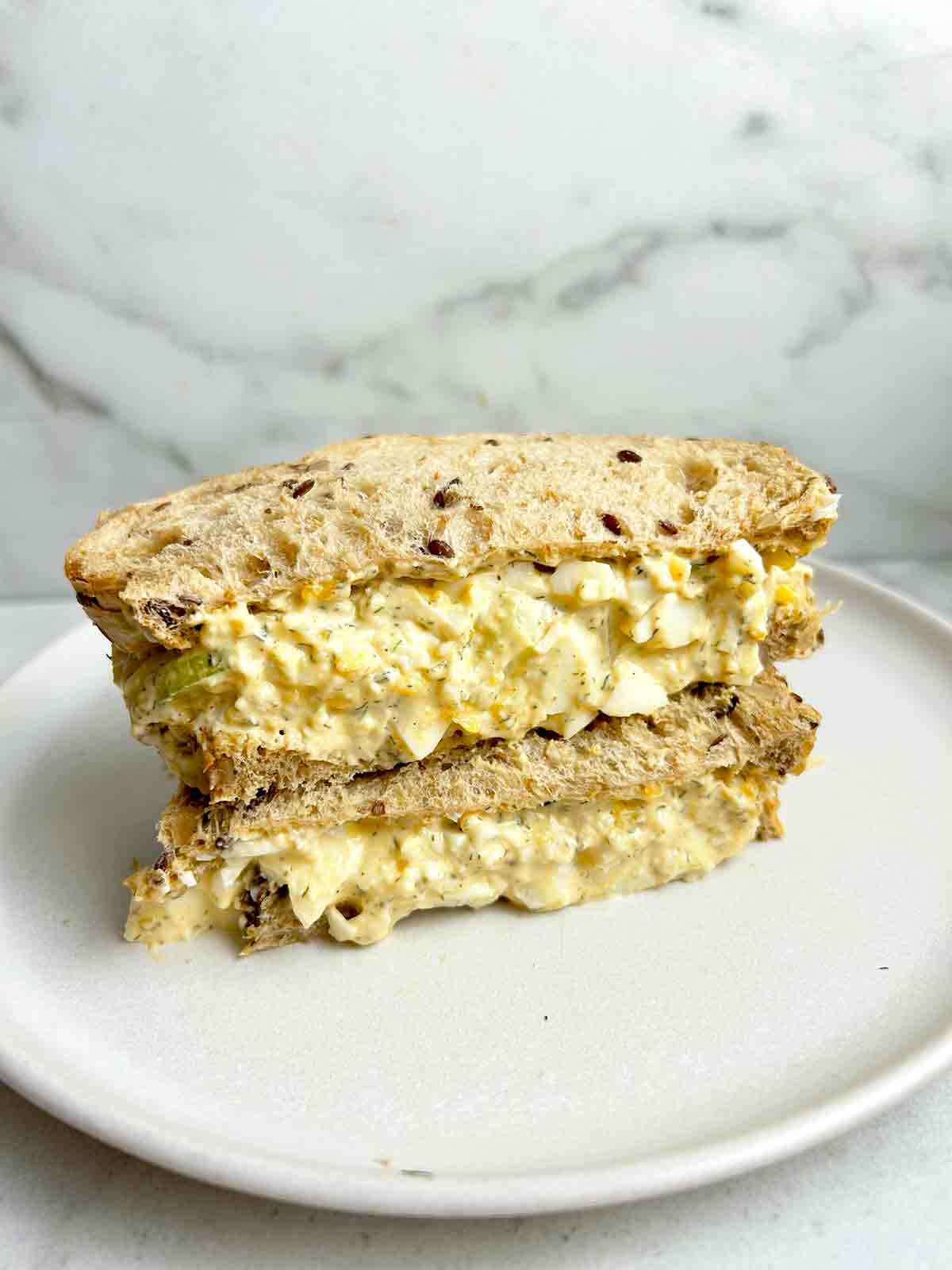 egg salad sandwich cut in half and stack on one another.