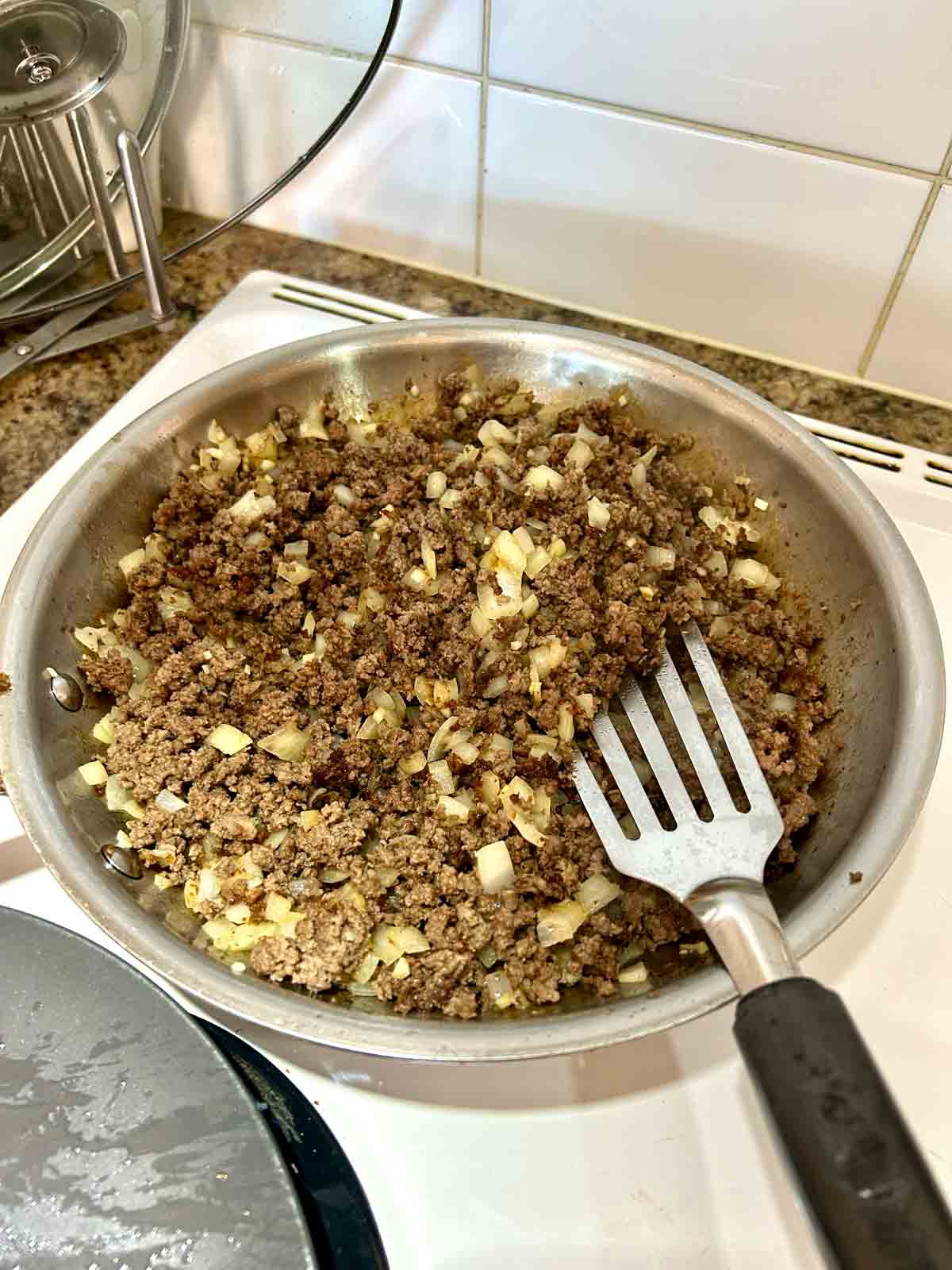 beef, onions, and garlic being sautéed in skillet.