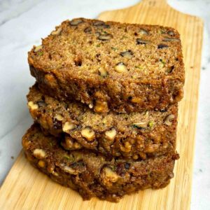 slices of zucchini bread stacked on wooden board.