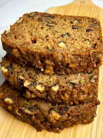 slices of zucchini bread stacked on wooden board.