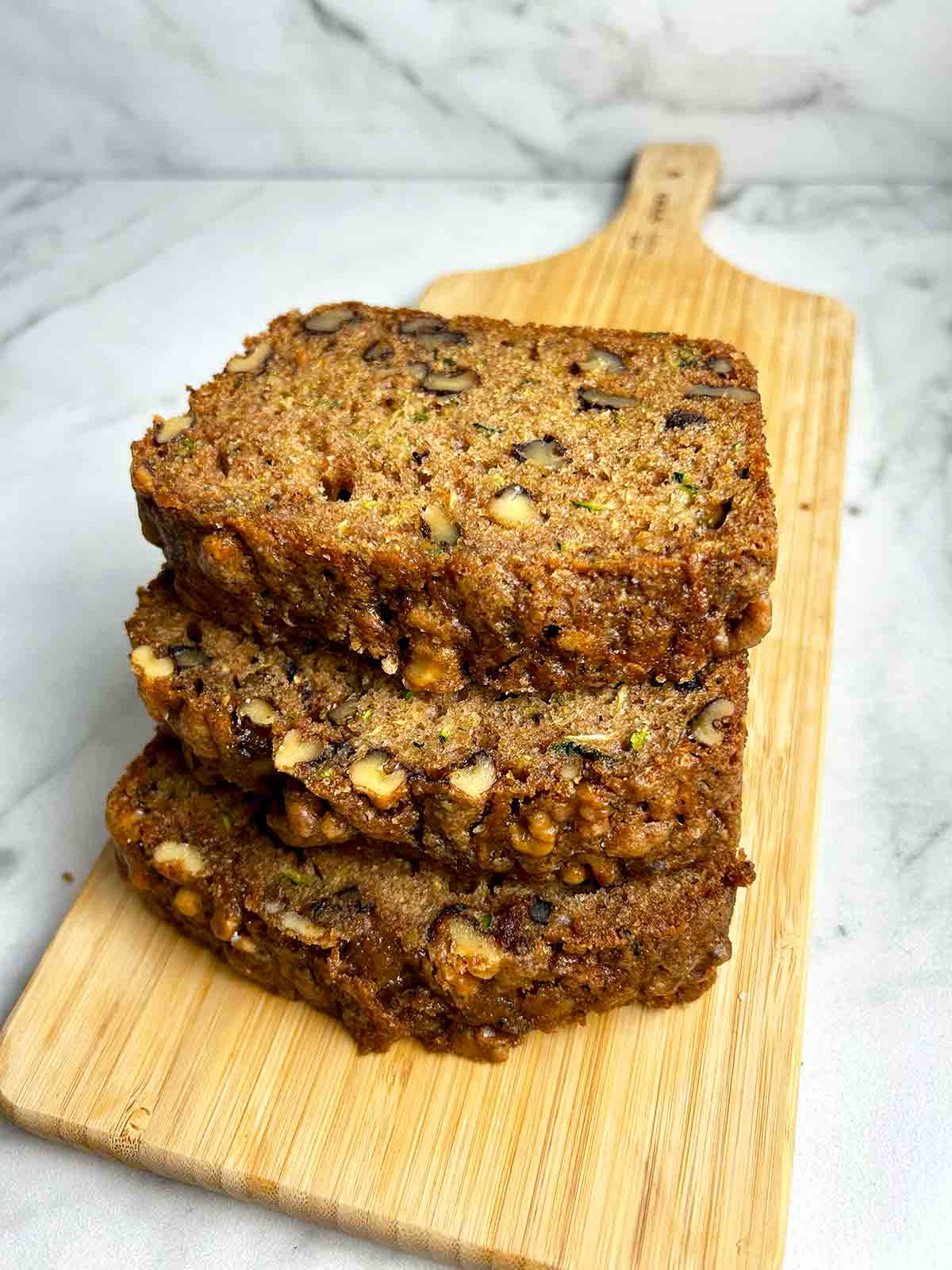 slices of zucchini bread stacked on wooden board.