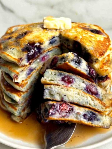 close up of stack of blueberry pancakes cut down the middle.