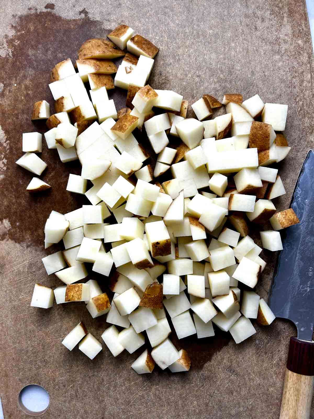potatoes unpeeled, chopped into small cubes on cutting board.