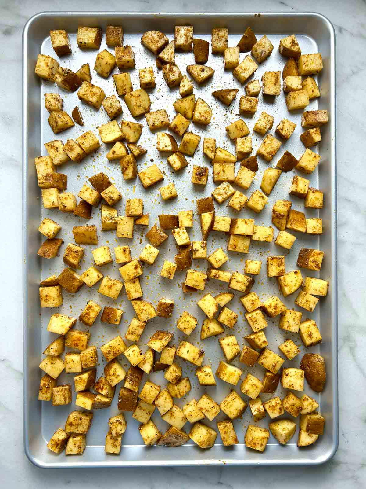 potatoes mixed with oil and spices, spread on baking sheet.