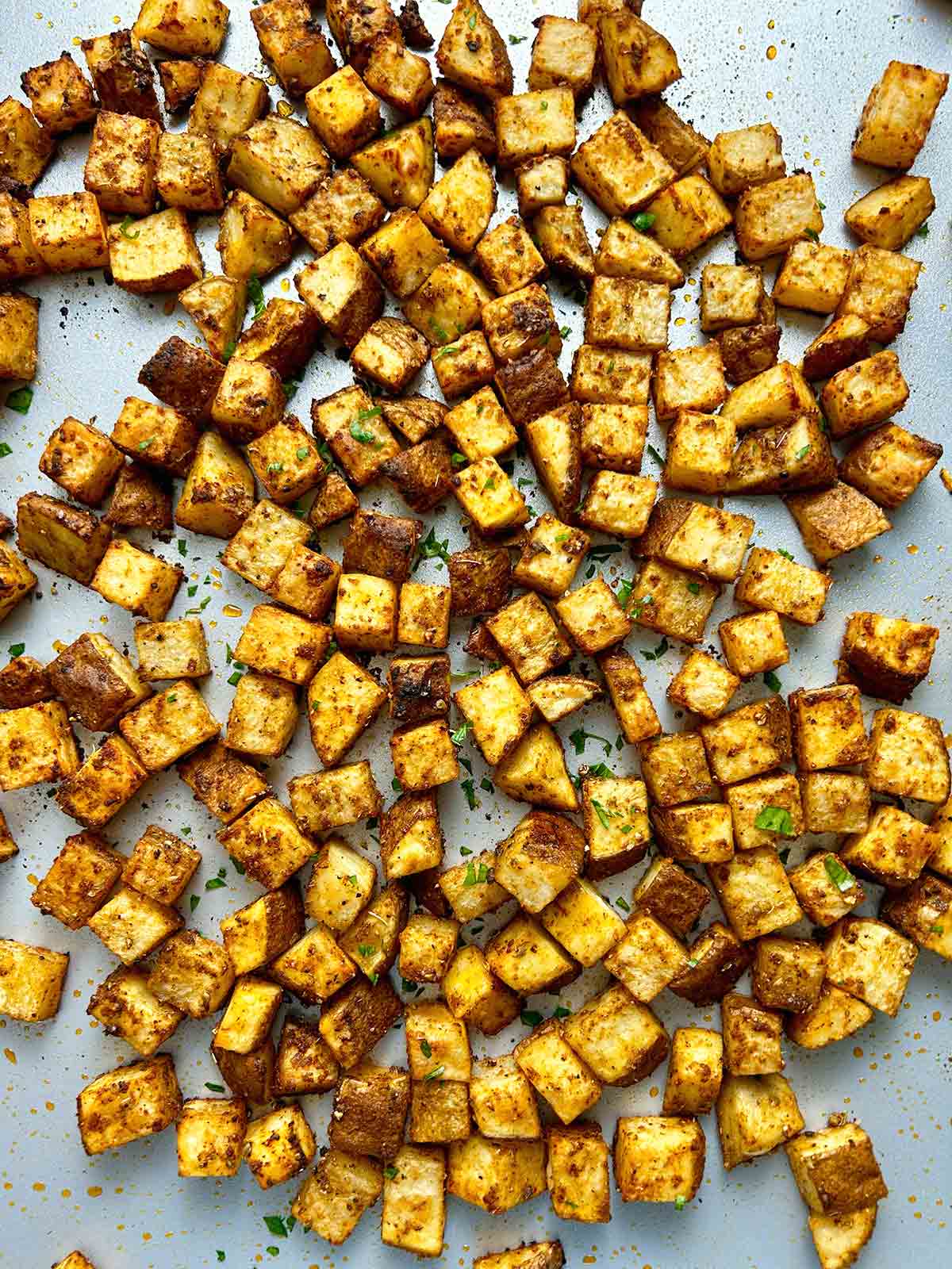 close up baked breakfast potatoes in baking sheet.