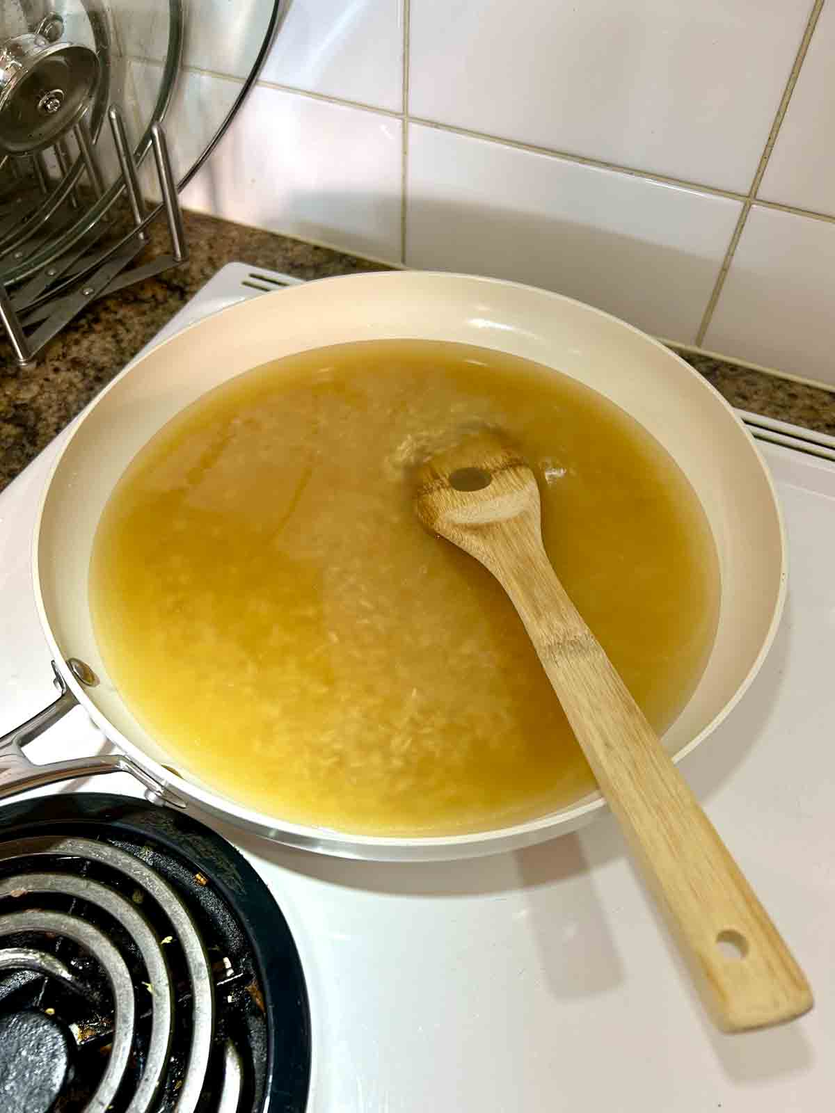 chicken broth added to rice in skillet.