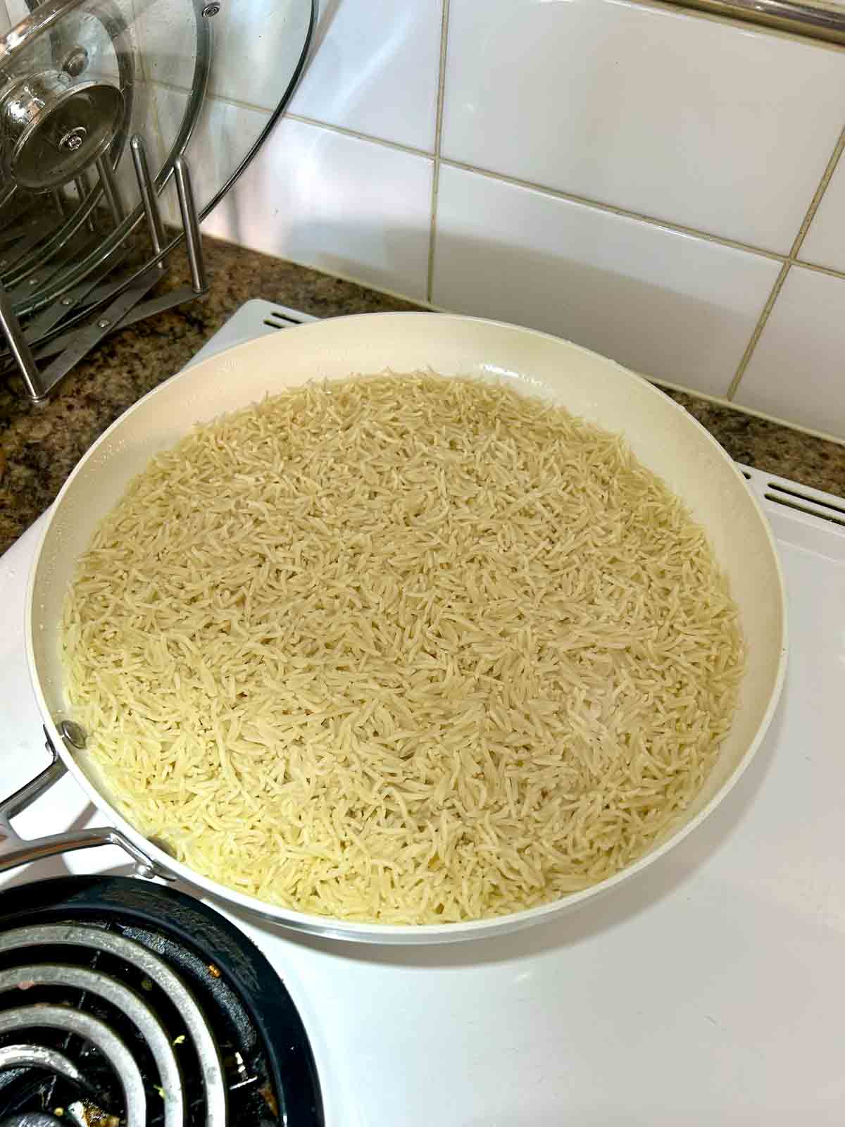 rice in skillet after being simmered; water is below the level of rice.