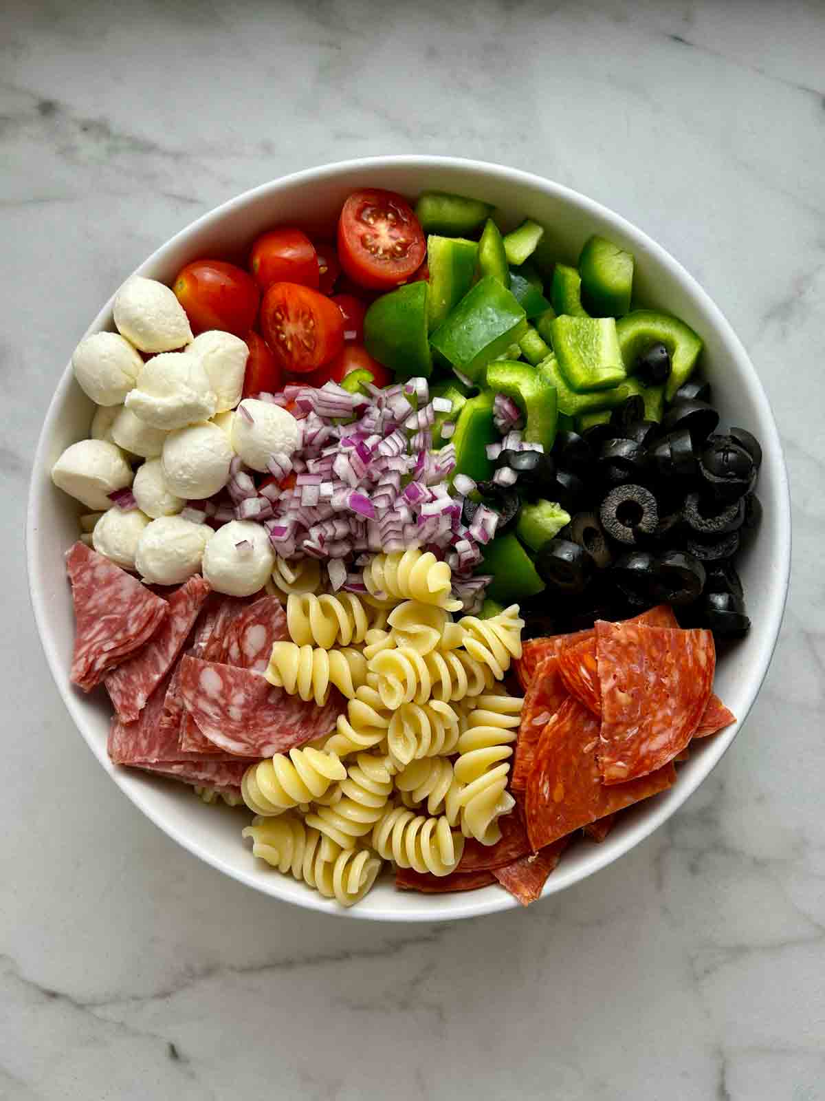 all components of pasta salad arranged in large bowl.