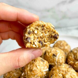 hand holding peanut butter energy ball with bite taken out of it.