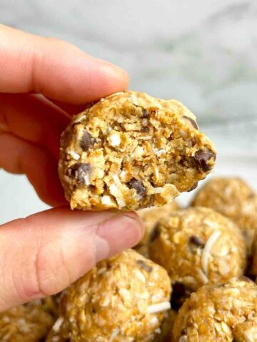 hand holding peanut butter energy ball with bite taken out of it.