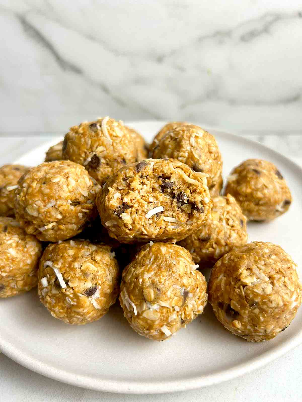 pile of peanut butter energy ball on plate; one has bite taken out of it.