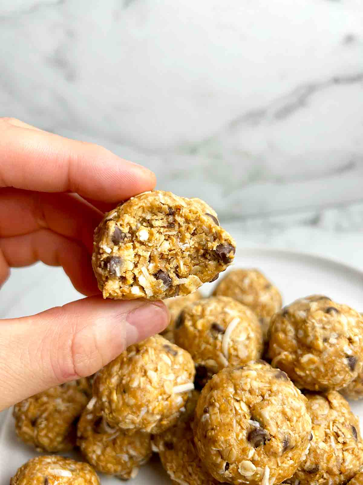 hand holding peanut butter energy ball with bite taken out of it.